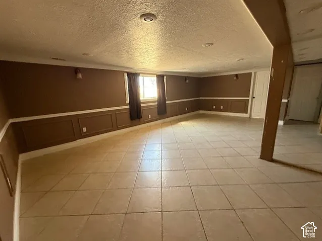 Below grade area featuring wainscoting, light tile patterned floors, and a decorative wall