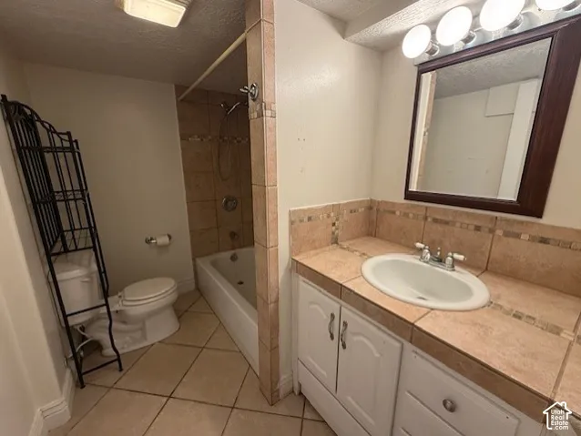 Bathroom featuring a textured ceiling, vanity, light tile patterned flooring, and bathtub / shower combination