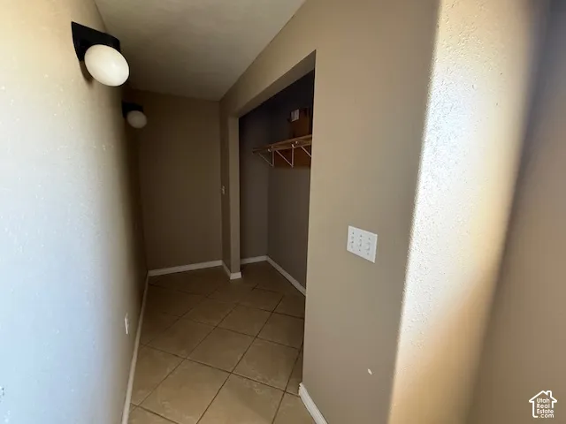 Hall featuring light tile patterned flooring and baseboards