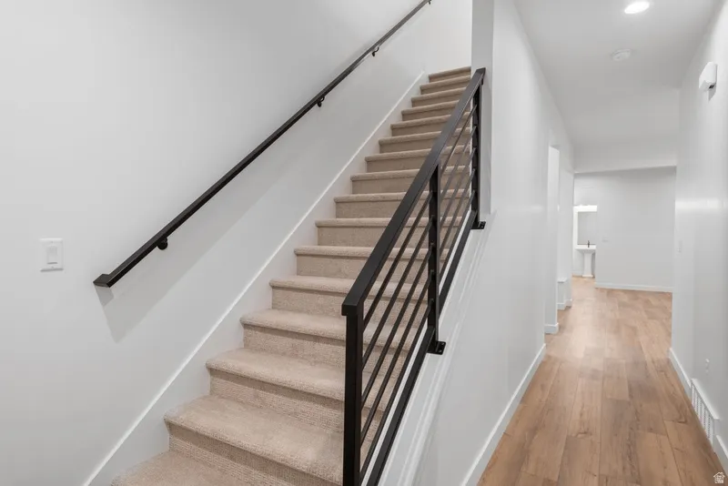 Stairs featuring wood finished floors and recessed lighting