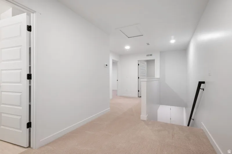 Hall featuring light carpet, recessed lighting, and an upstairs landing