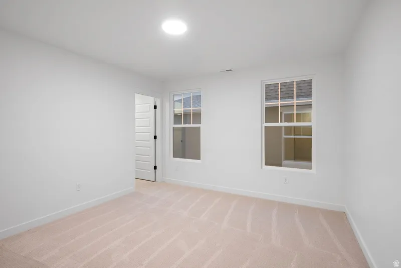 Unfurnished room with light colored carpet and baseboards
