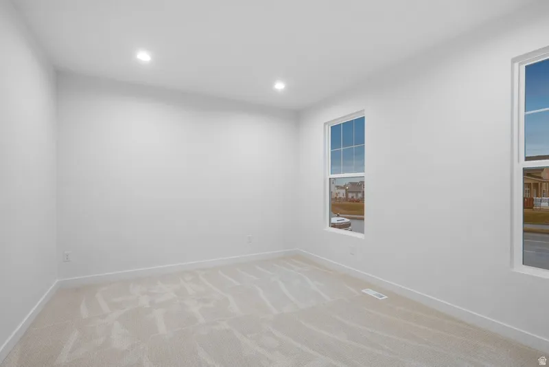 Spare room featuring light colored carpet and recessed lighting
