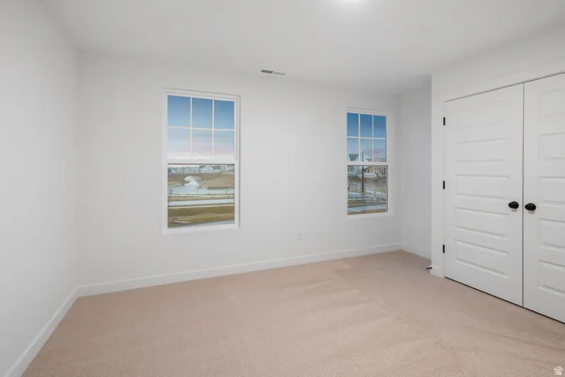 Unfurnished bedroom with light colored carpet and a closet