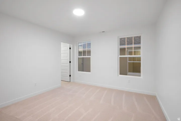 Unfurnished room with light colored carpet and baseboards