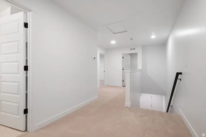 Hall featuring light carpet, recessed lighting, and an upstairs landing