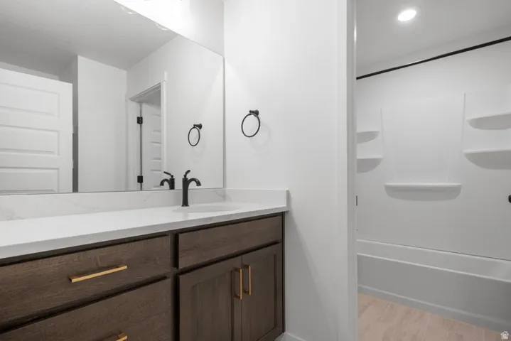 Full bathroom featuring vanity, recessed lighting, and light wood-style floors