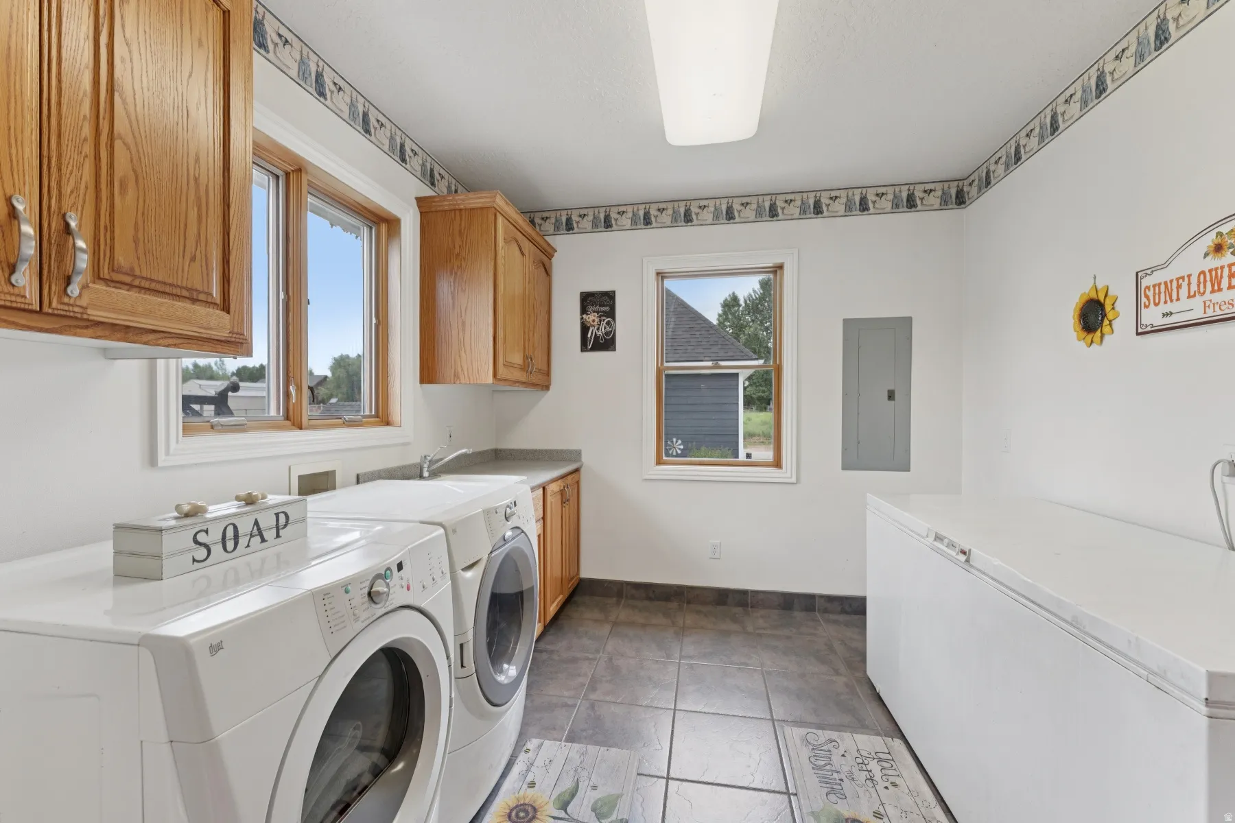 Laundry room featuring separate washer and dryer, electric panel, and cabinet space