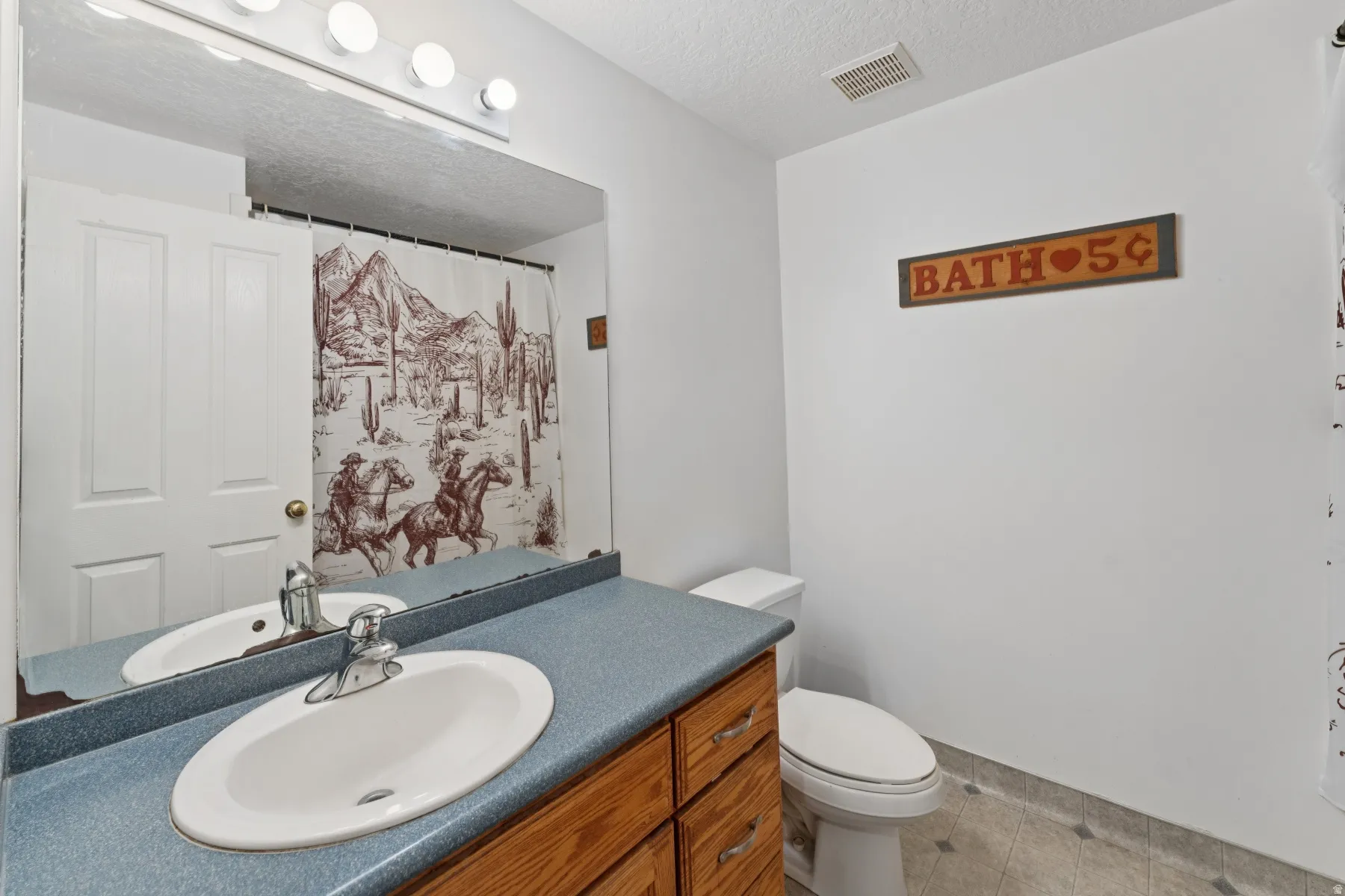 Bathroom with a textured ceiling, vanity, a shower with shower curtain, and light tile patterned floors