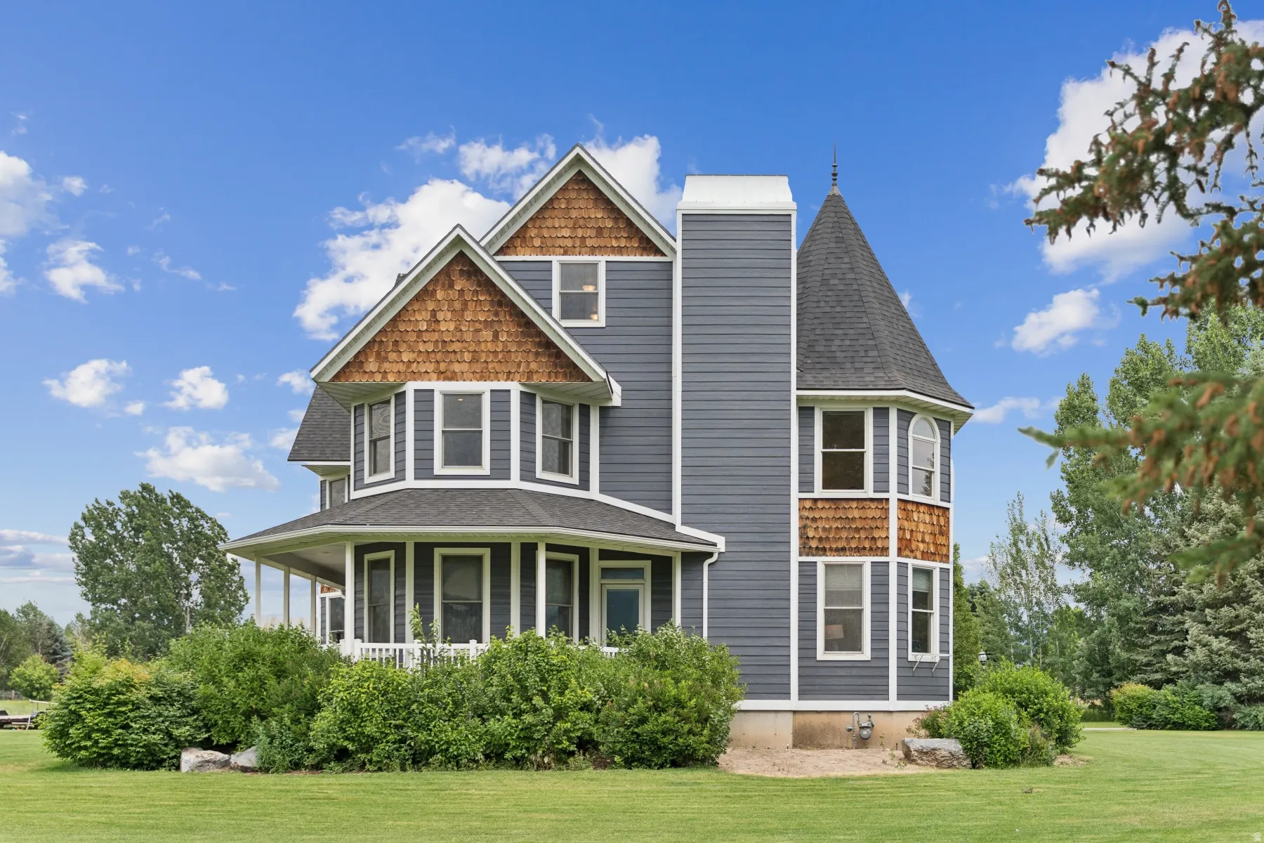 View of front of property featuring a shingled roof, a front yard, and a porch