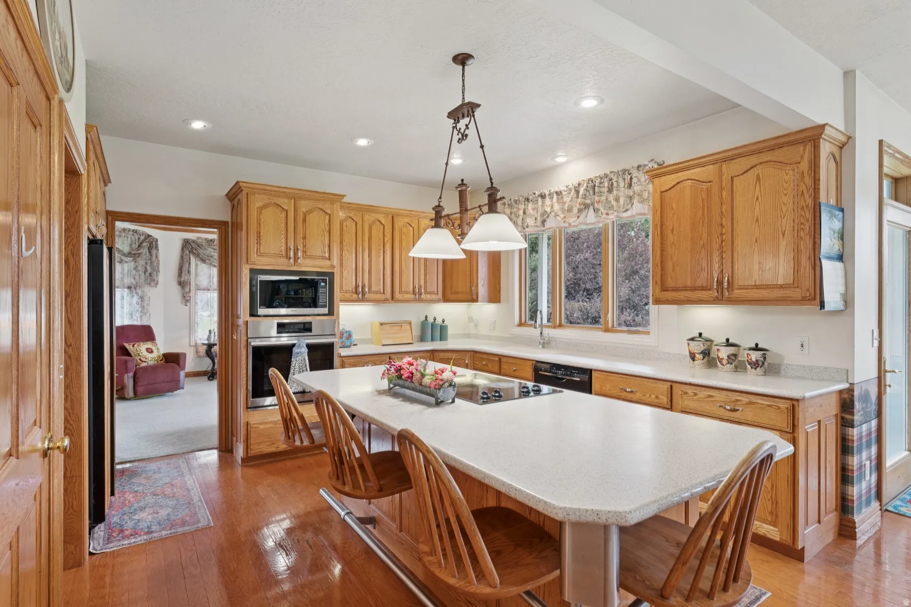 Kitchen with a breakfast bar, stainless steel appliances, hanging light fixtures, a kitchen island, and light wood finished floors