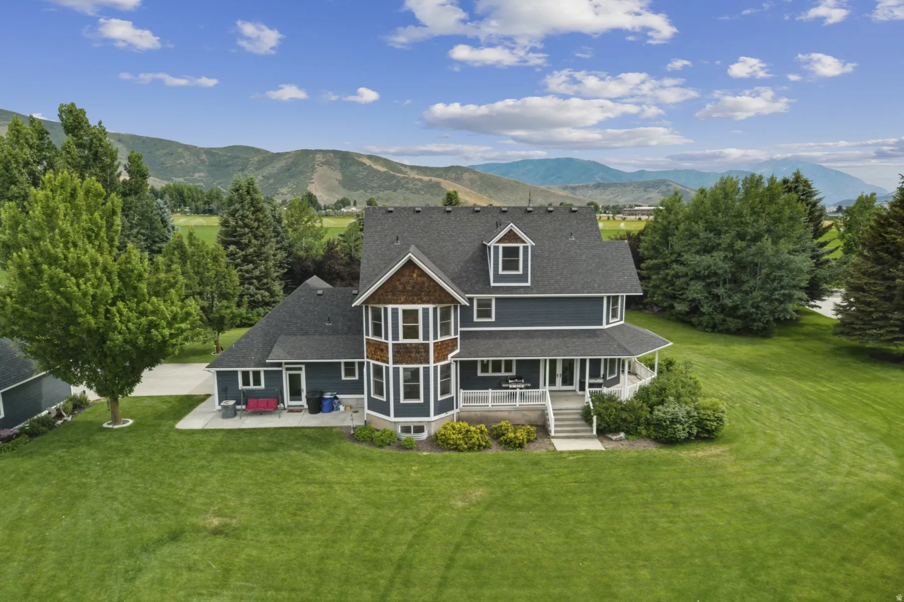 Back of property with a lawn, a mountain view, a sunroom, and a patio area