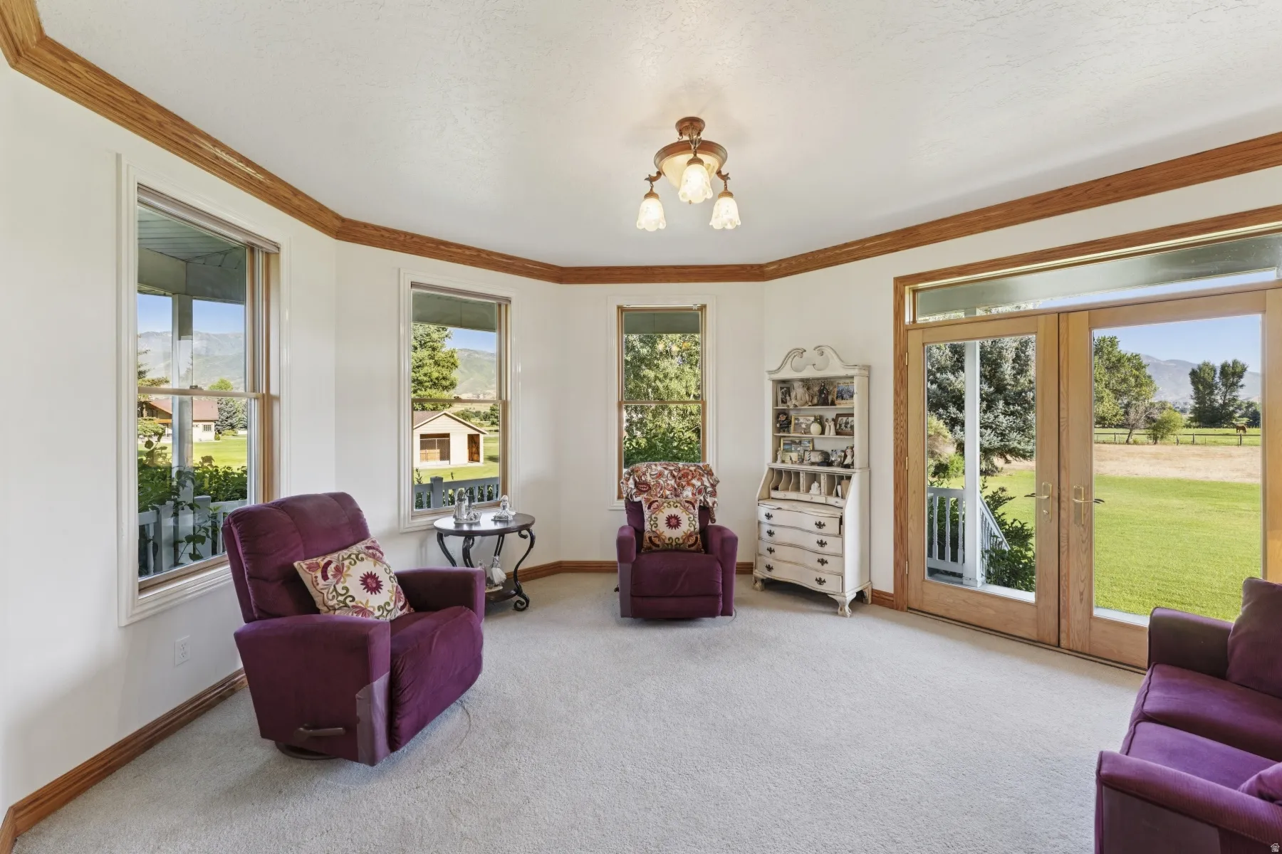 Living area with carpet, french doors, a chandelier, crown molding, and a mountain view