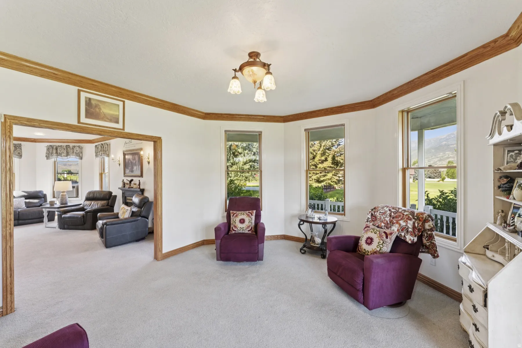 Living area featuring plenty of natural light, suspended lighting, light carpet, and crown molding