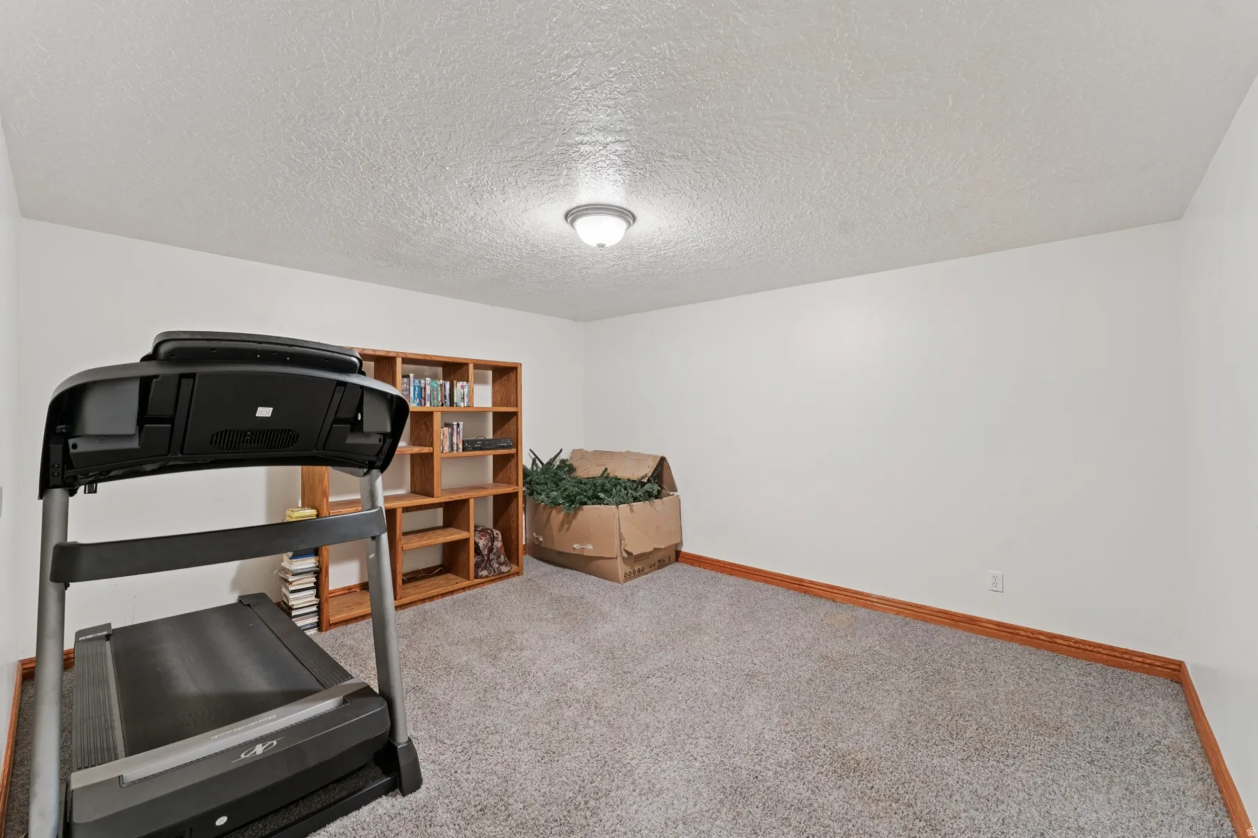 Workout room with light colored carpet and a textured ceiling