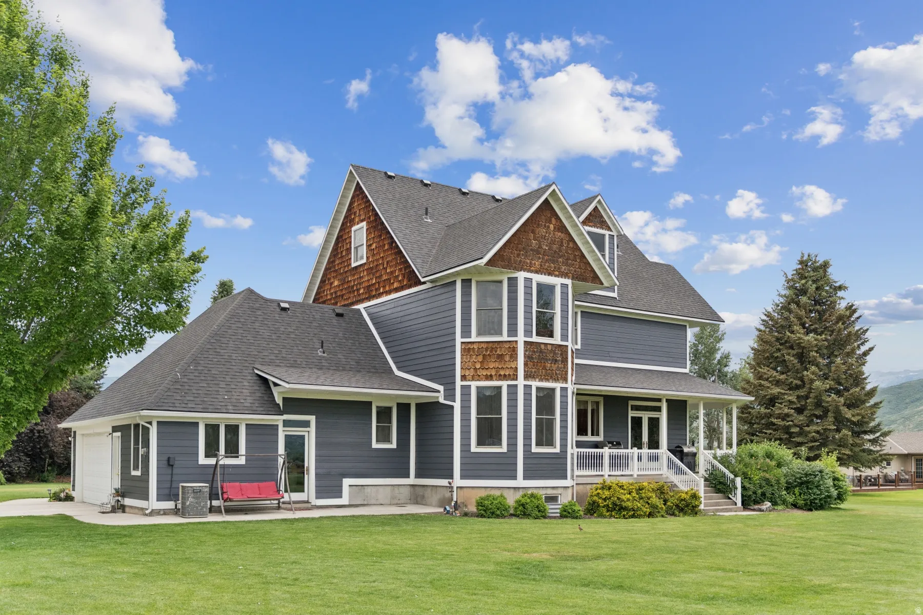 Rear view of property with a yard, roof with shingles, covered porch, and a garage