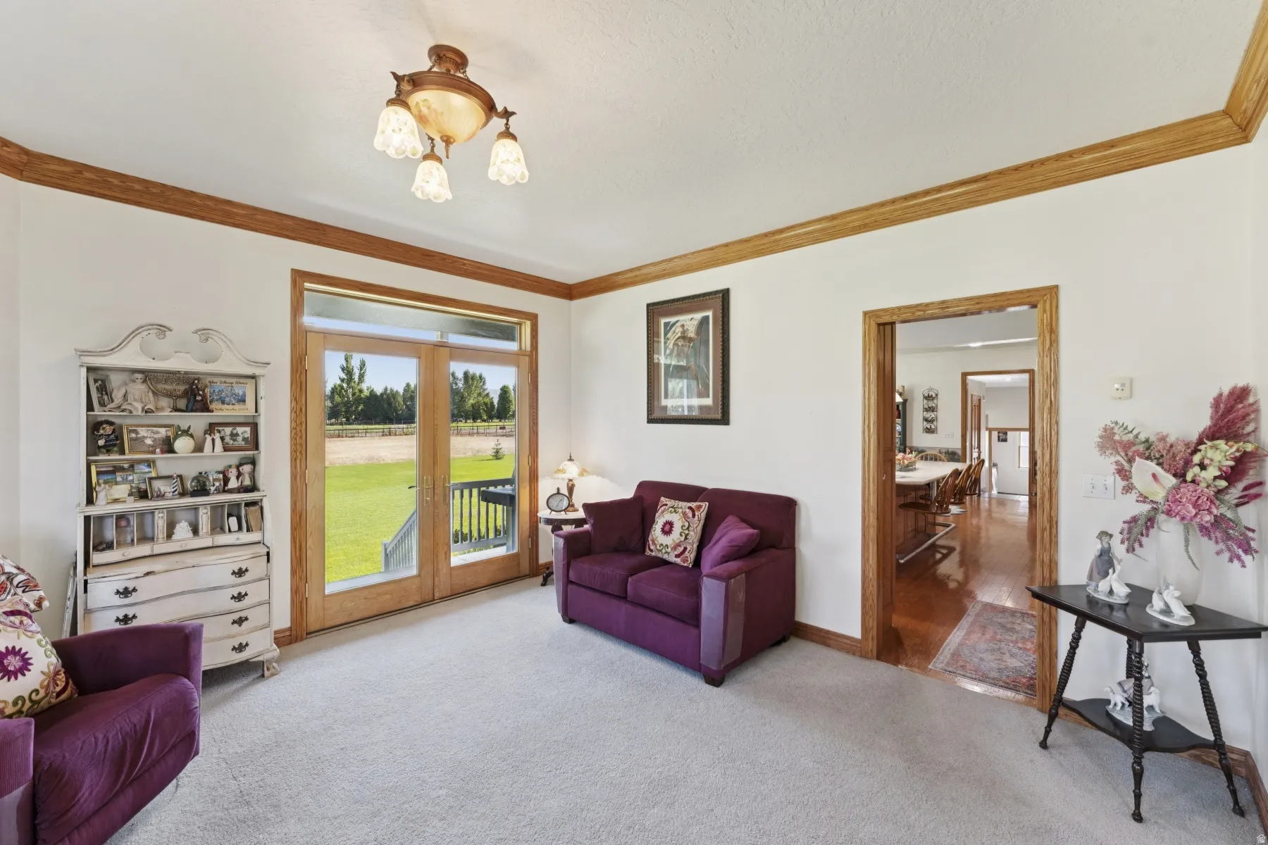 Living room with french doors, crown molding, and light carpet