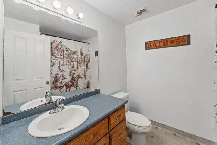 Bathroom with a textured ceiling, vanity, a shower with shower curtain, and light tile patterned floors