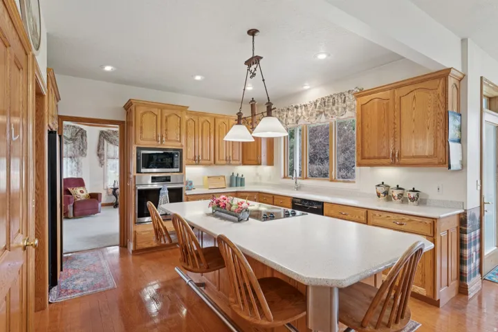 Kitchen with a breakfast bar, stainless steel appliances, hanging light fixtures, a kitchen island, and light wood finished floors