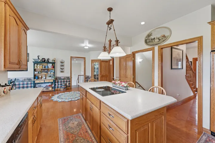 Kitchen with light wood-style flooring, a kitchen island, hanging light fixtures, black appliances, and wood finish cabinetry
