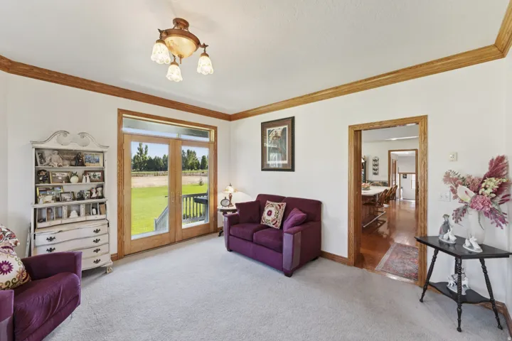 Living room with french doors, crown molding, and light carpet