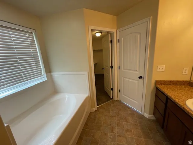 Bathroom featuring vanity, a bath, and a walk in closet