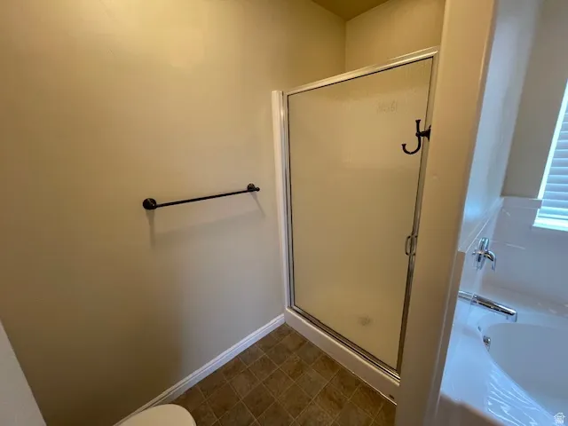 Full bath featuring a shower stall, a garden tub, and dark flooring