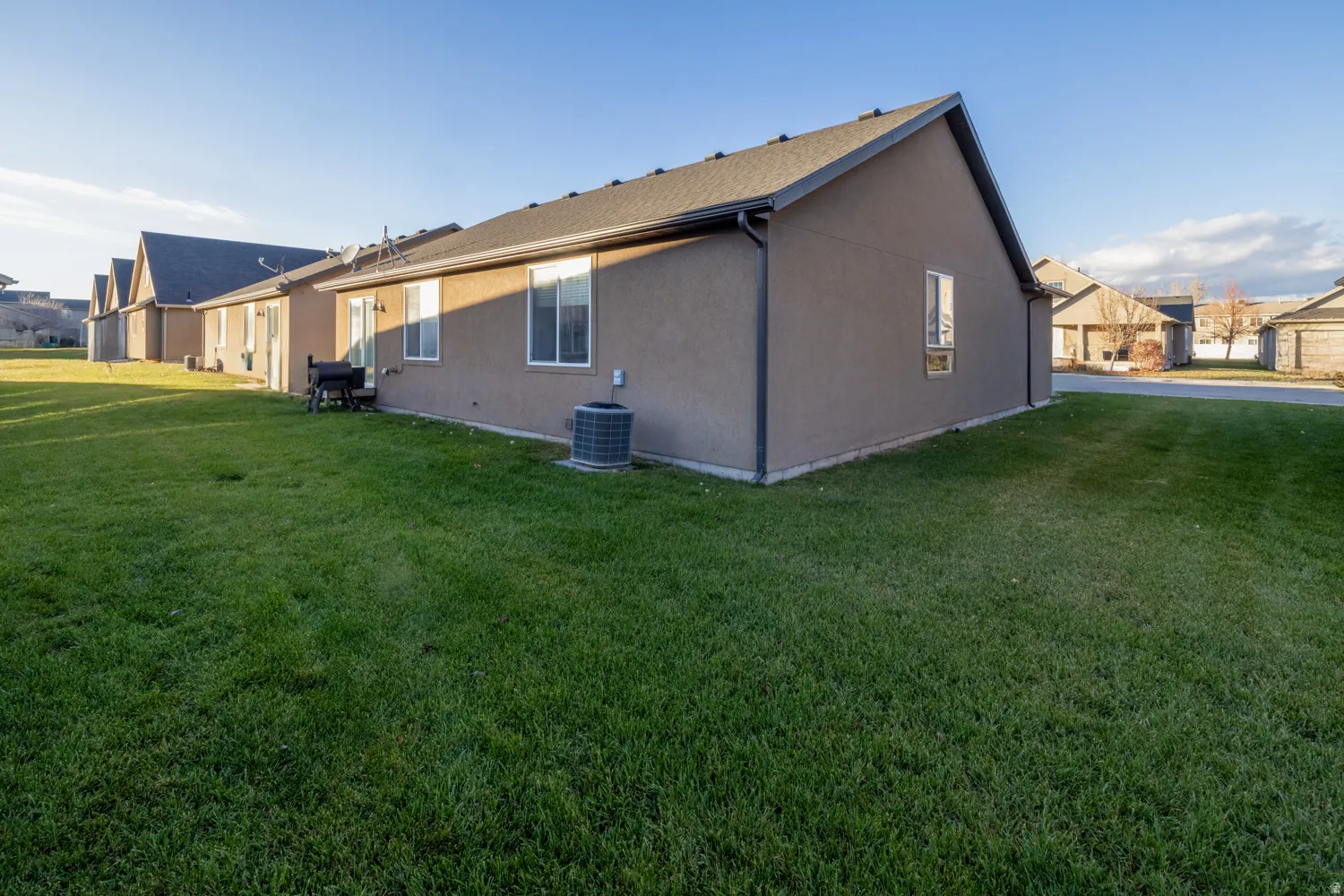 Rear view of house with a lawn and stucco siding