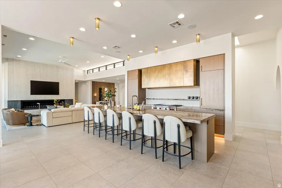 Kitchen featuring a kitchen bar, a large island, open floor plan, a ceiling fan, and recessed lighting