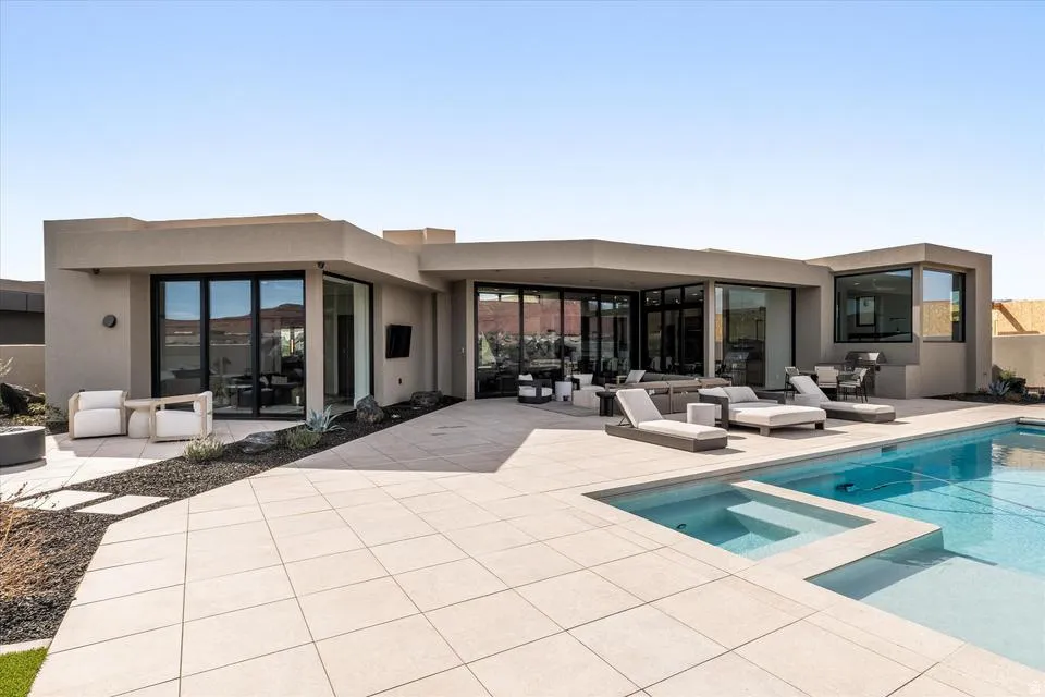 Rear view of property with a patio, a pool with connected hot tub, and stucco siding