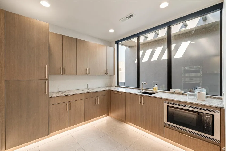 Kitchen featuring light stone countertops, stainless steel microwave, and recessed lighting
