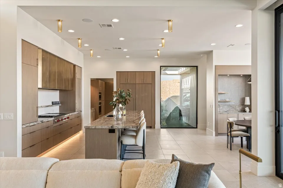 Kitchen featuring a breakfast bar area, a center island with sink, tasteful backsplash, recessed lighting, and stainless steel gas cooktop