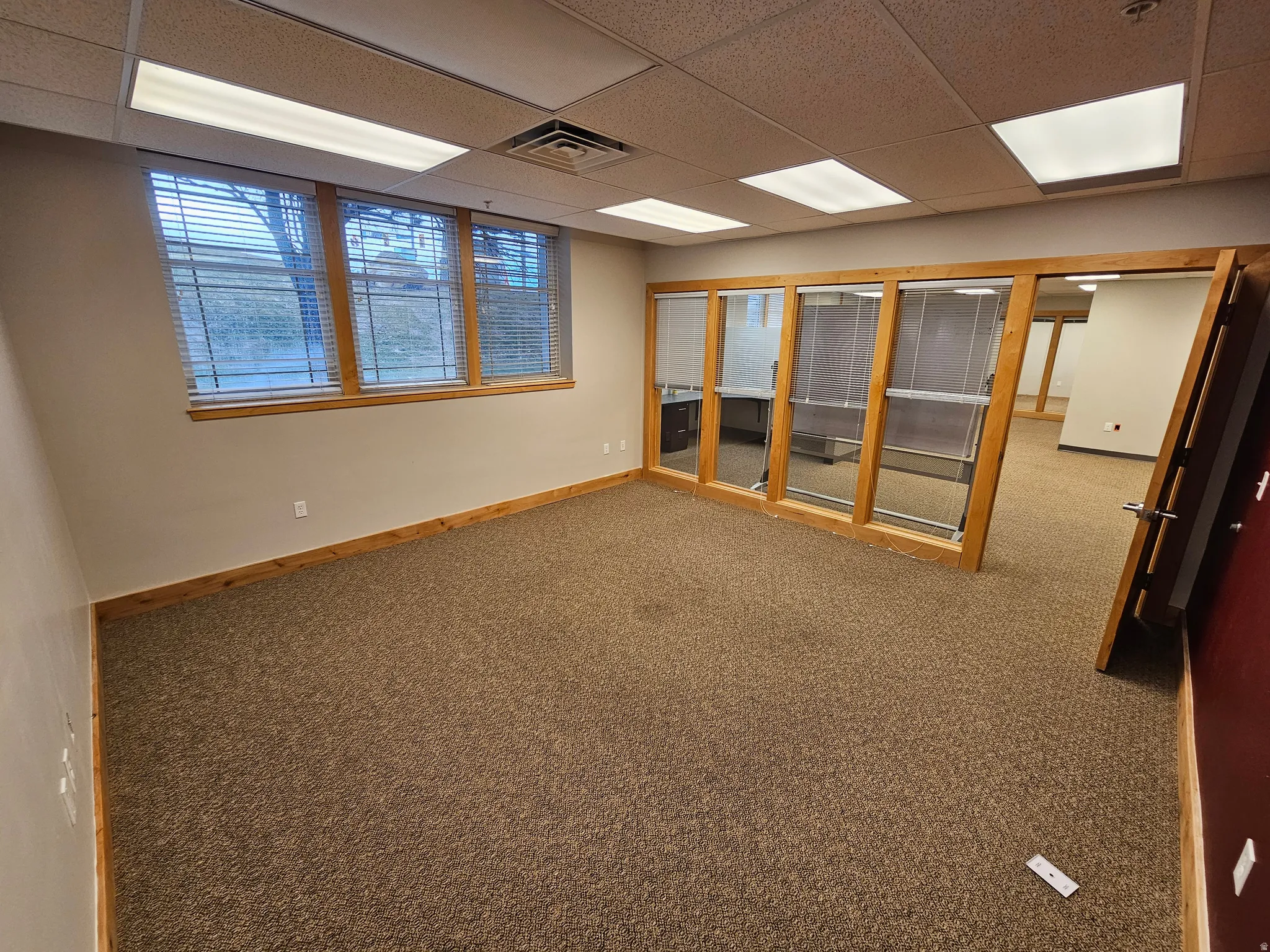Carpeted empty room with baseboards and a paneled ceiling