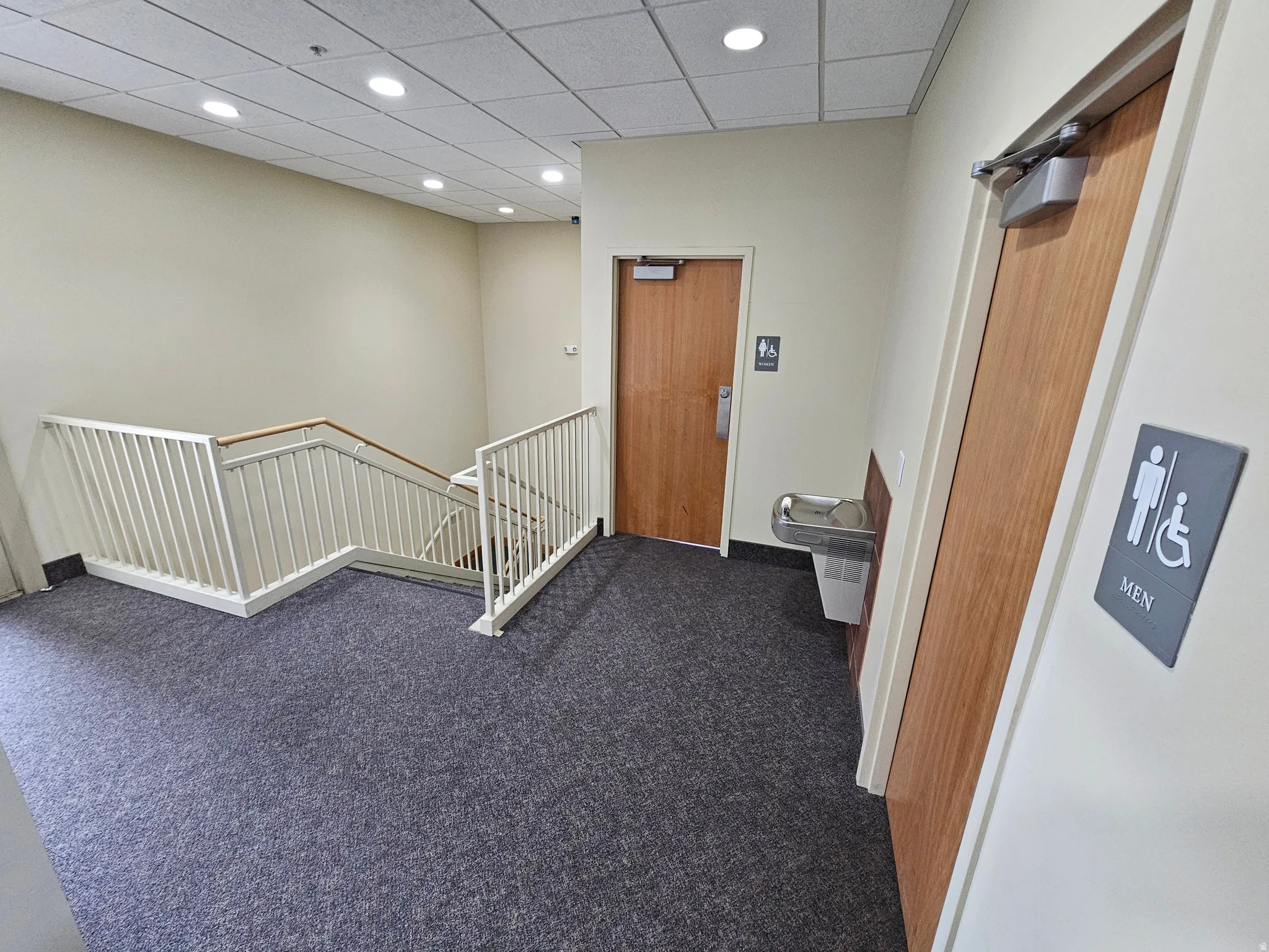 Hallway featuring an upstairs landing, a paneled ceiling, carpet floors, and recessed lighting