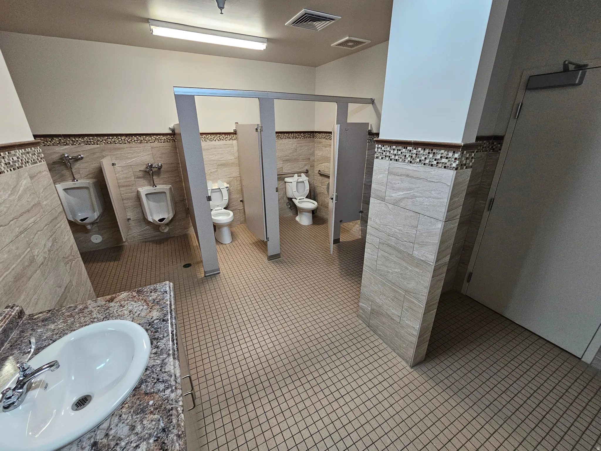 Bathroom with tile walls, tile patterned floors, vanity, and a wainscoted wall