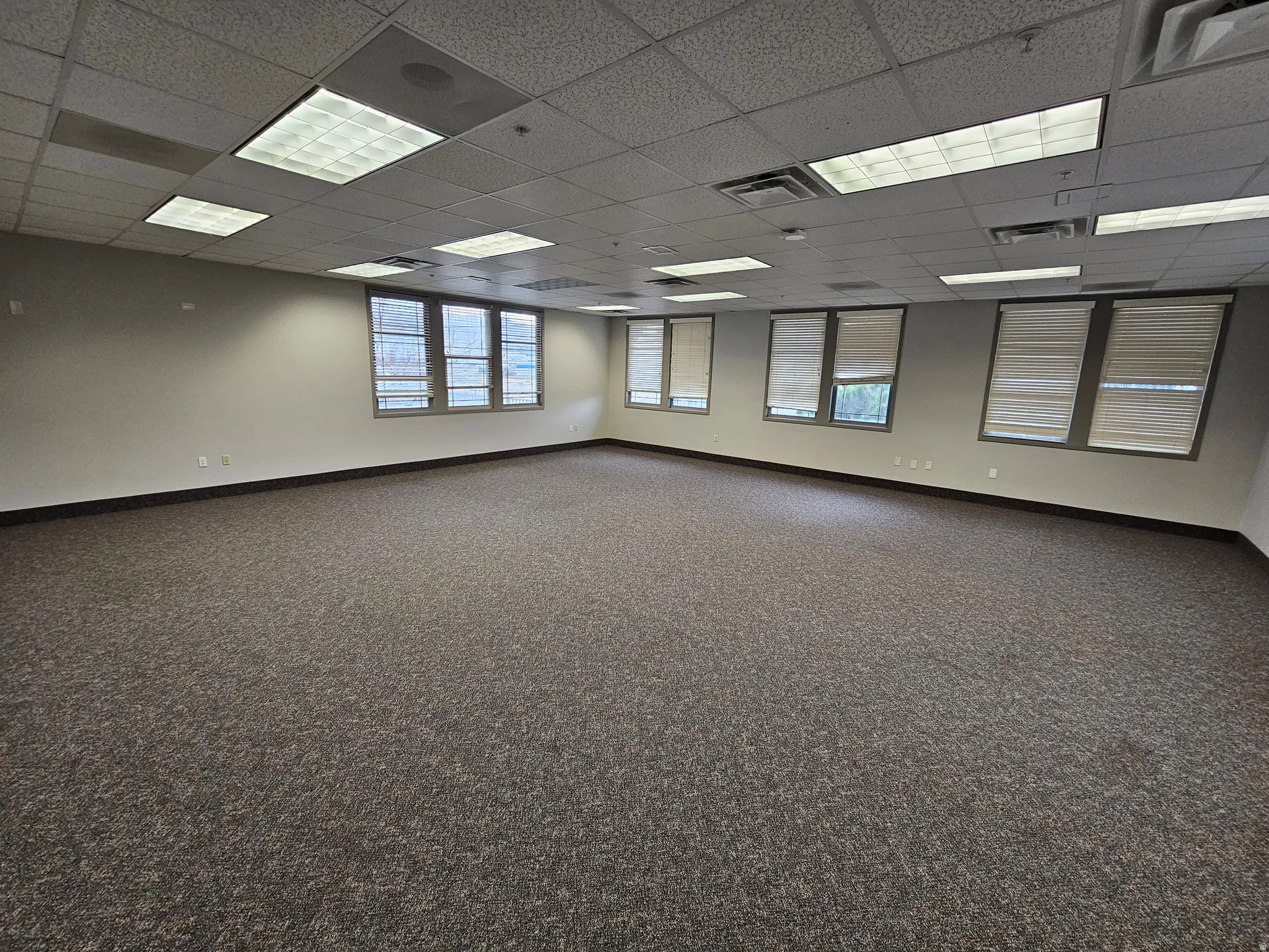 Spare room featuring a paneled ceiling and dark colored carpet