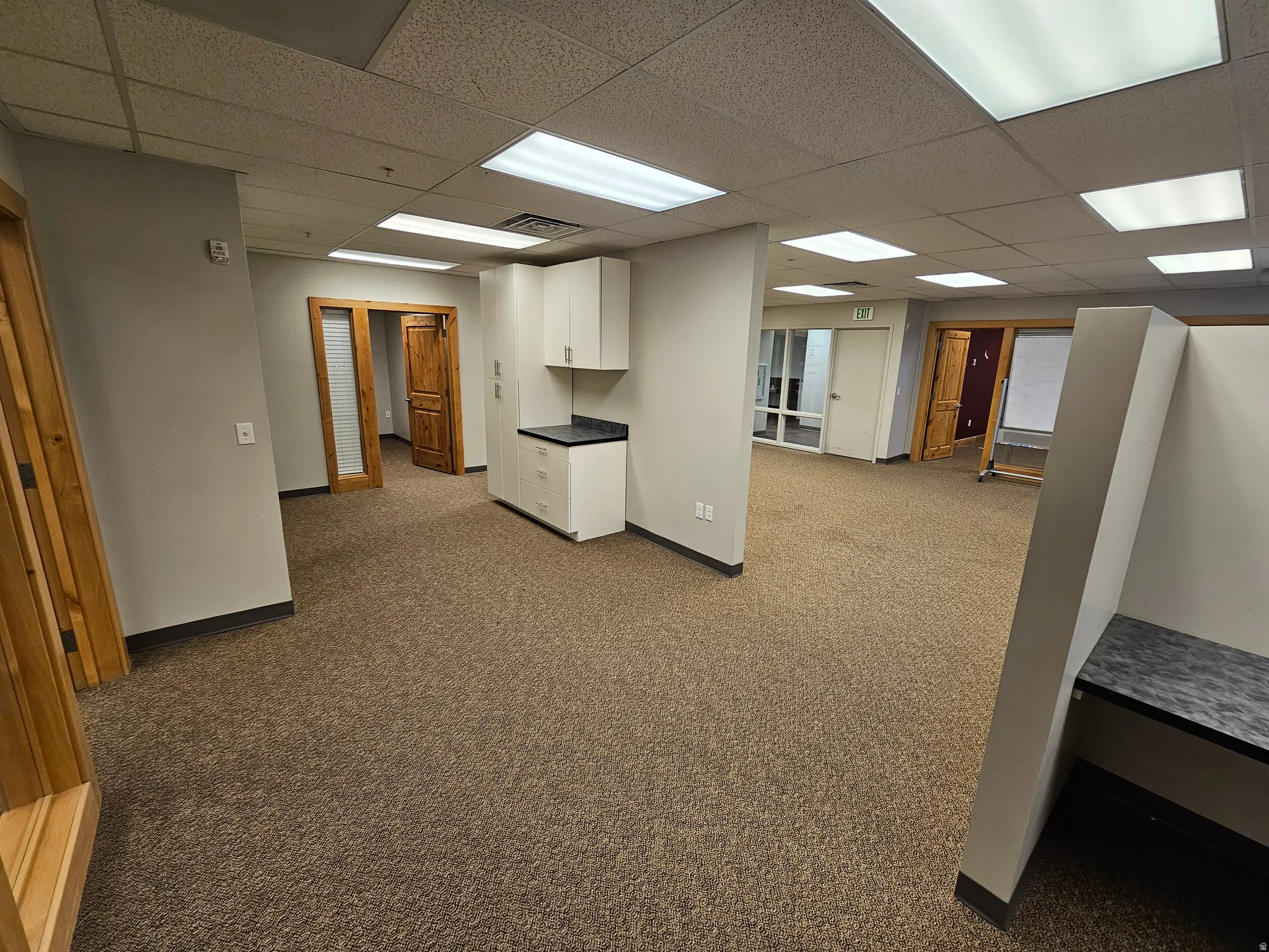 Basement featuring dark carpet and a drop ceiling