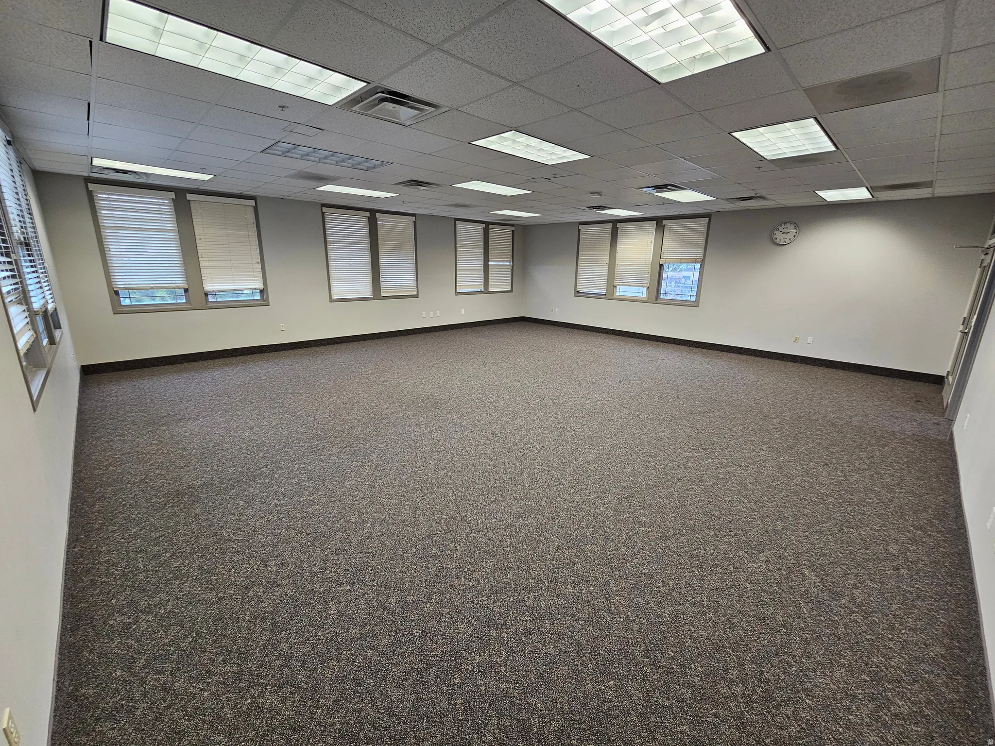 Carpeted empty room with baseboards and a paneled ceiling