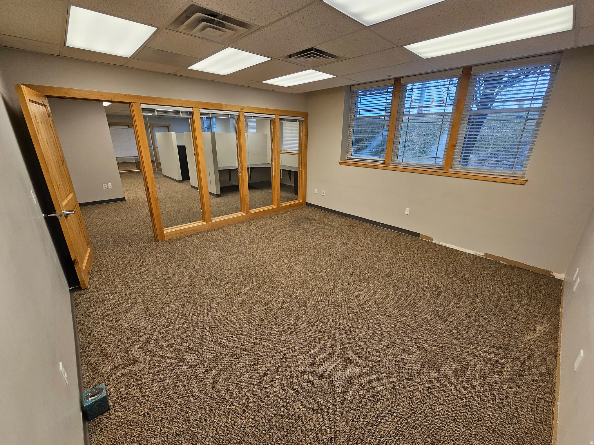 Carpeted spare room with a drop ceiling and baseboards
