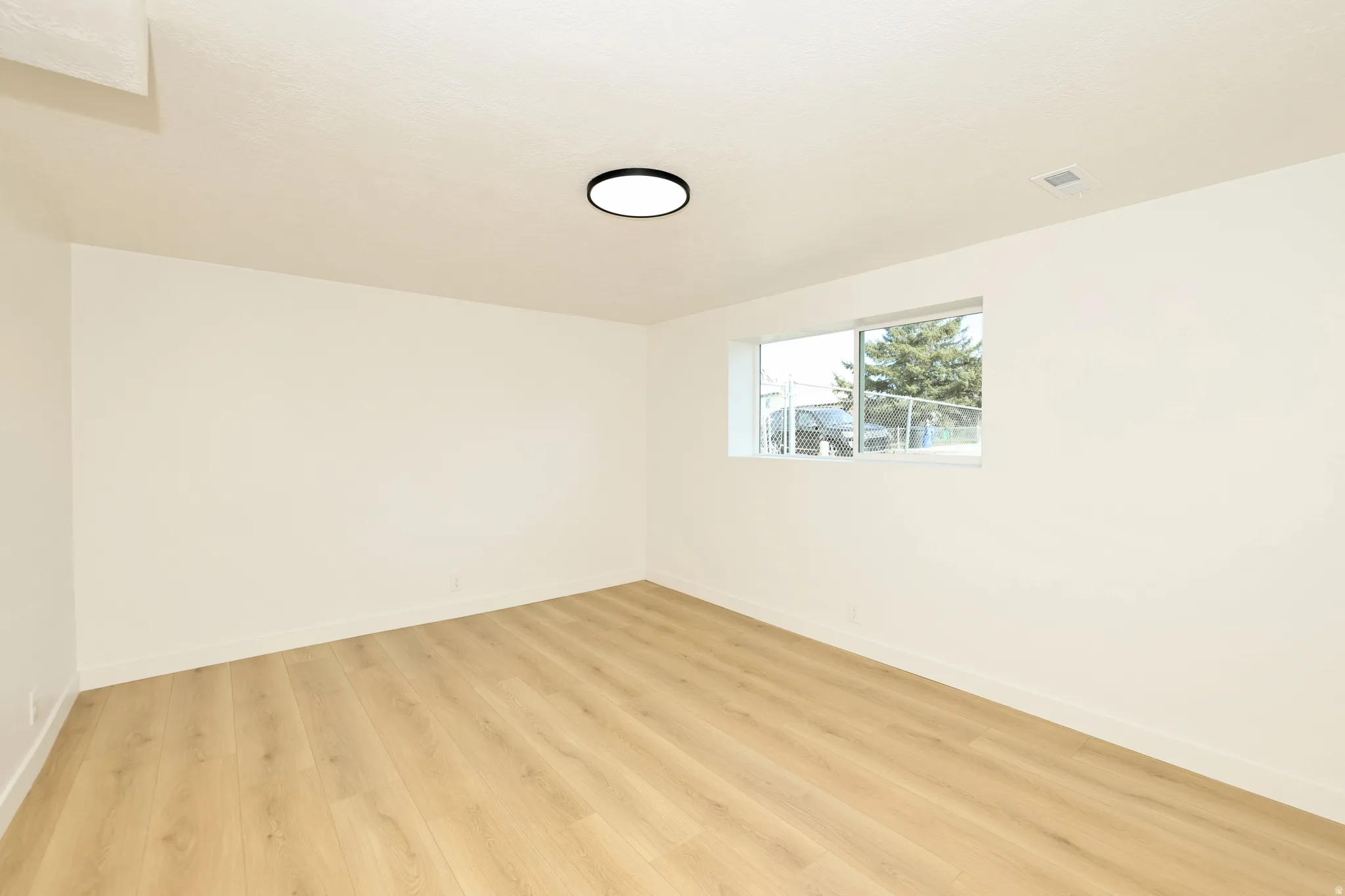 Spare room featuring light wood-style flooring and baseboards