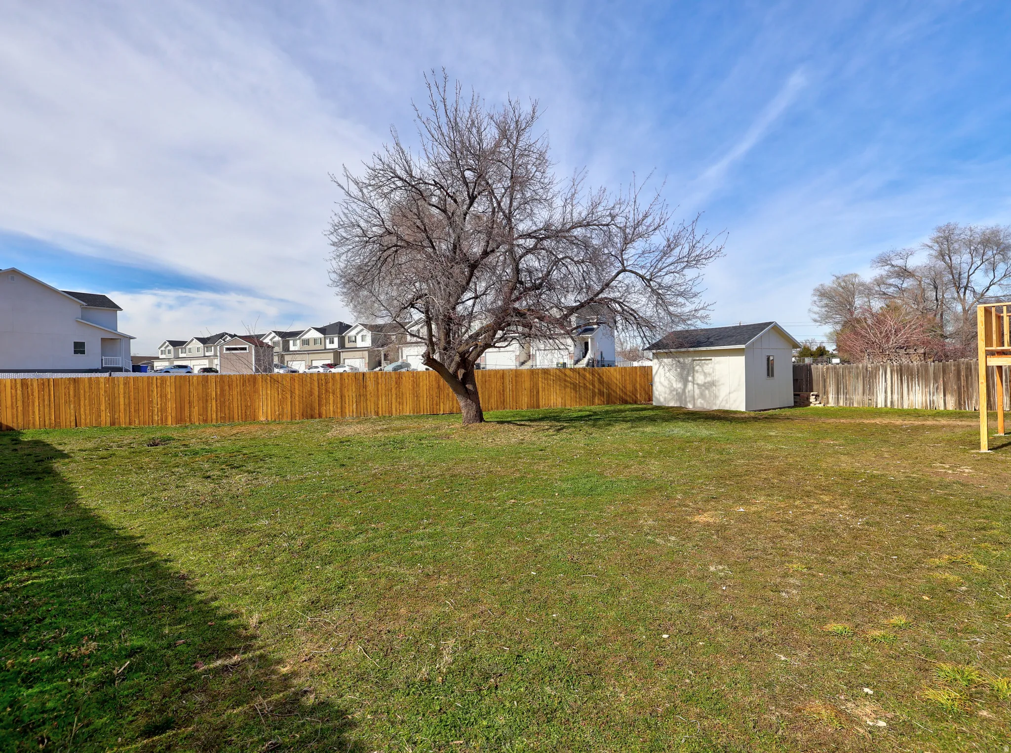 Fenced backyard with a residential view and a storage unit