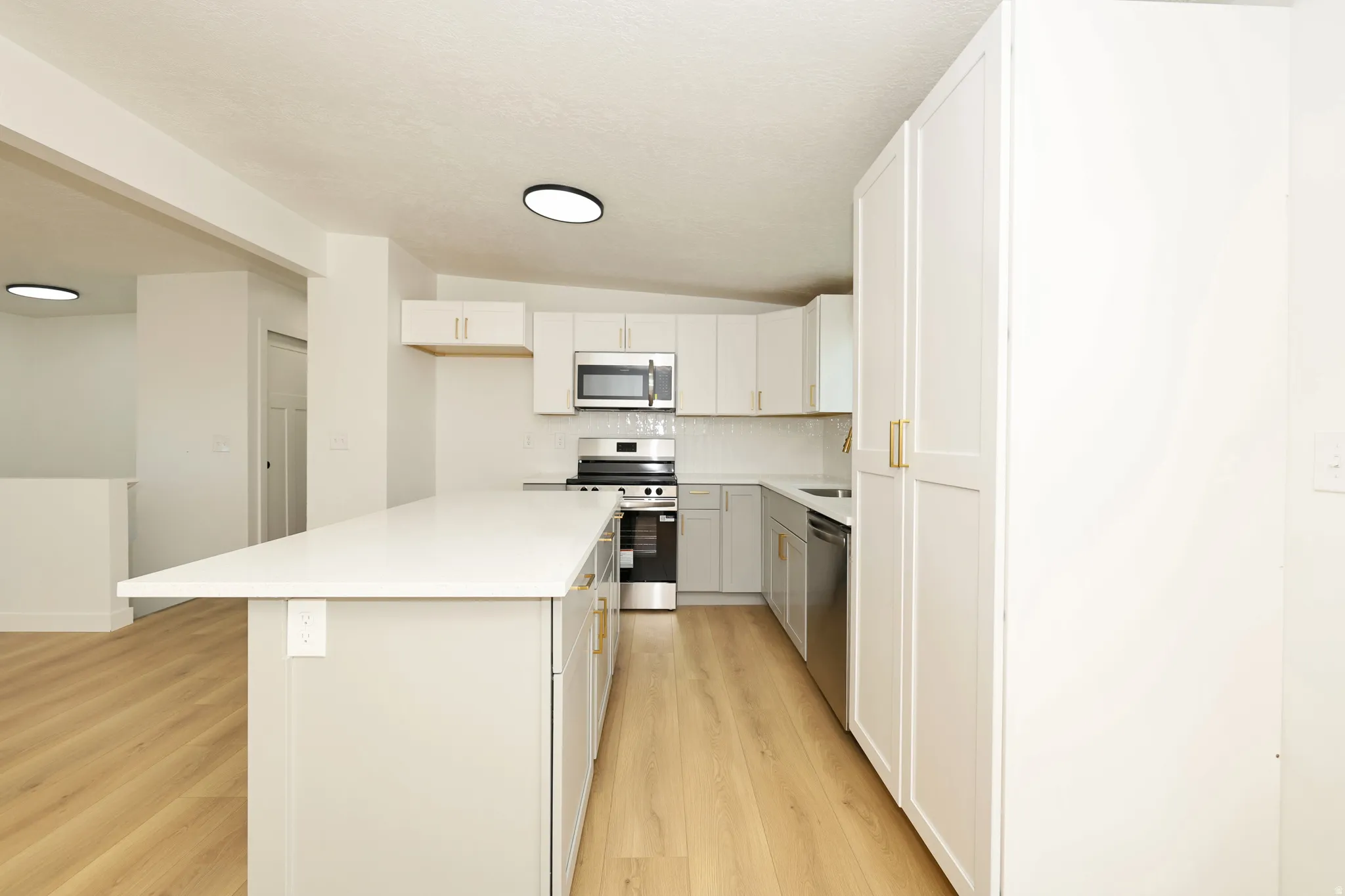 Kitchen with a center island, stainless steel appliances, white cabinetry, decorative backsplash, and lofted ceiling