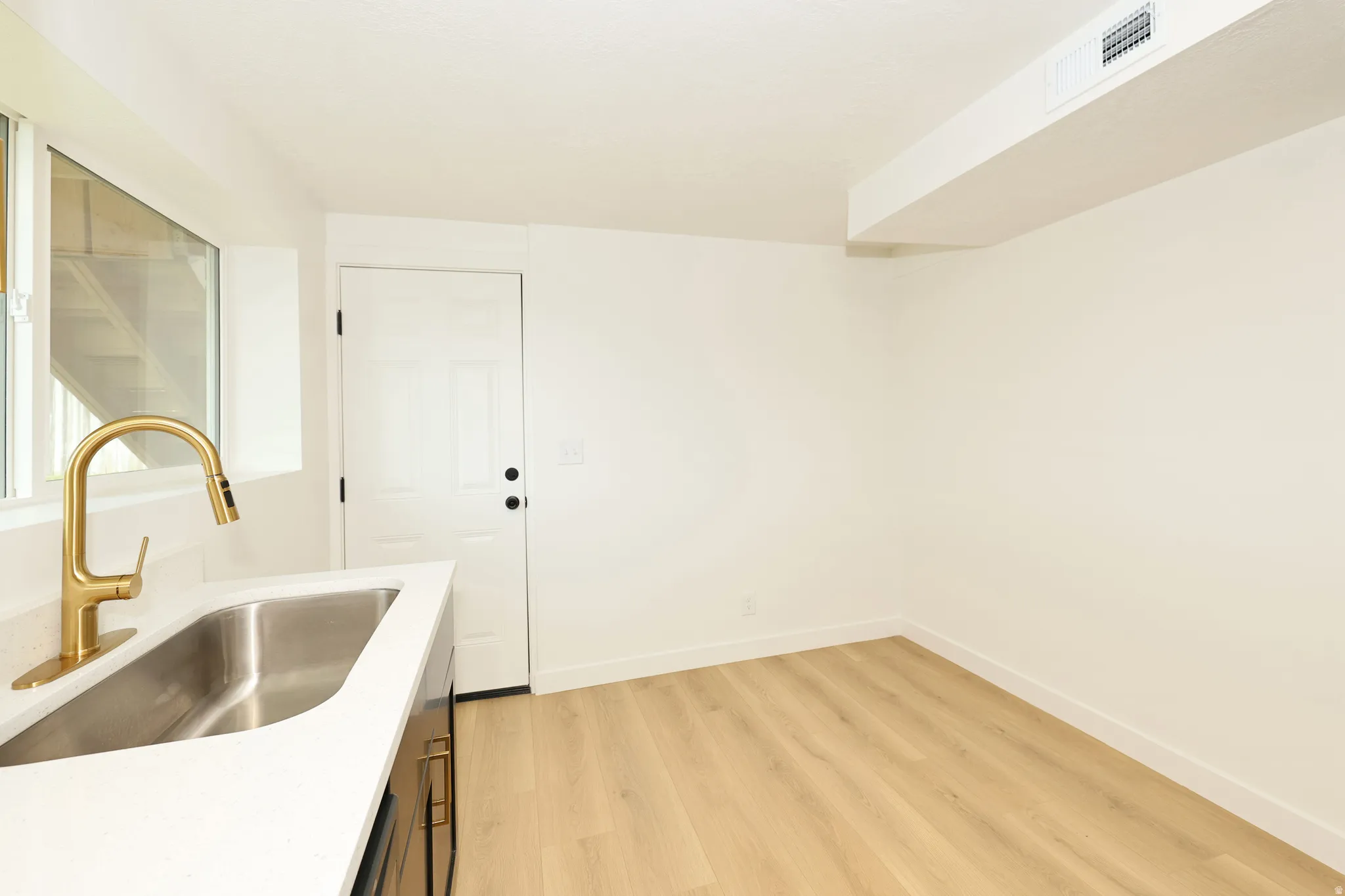 Kitchen featuring light wood-style floors and light stone counters
