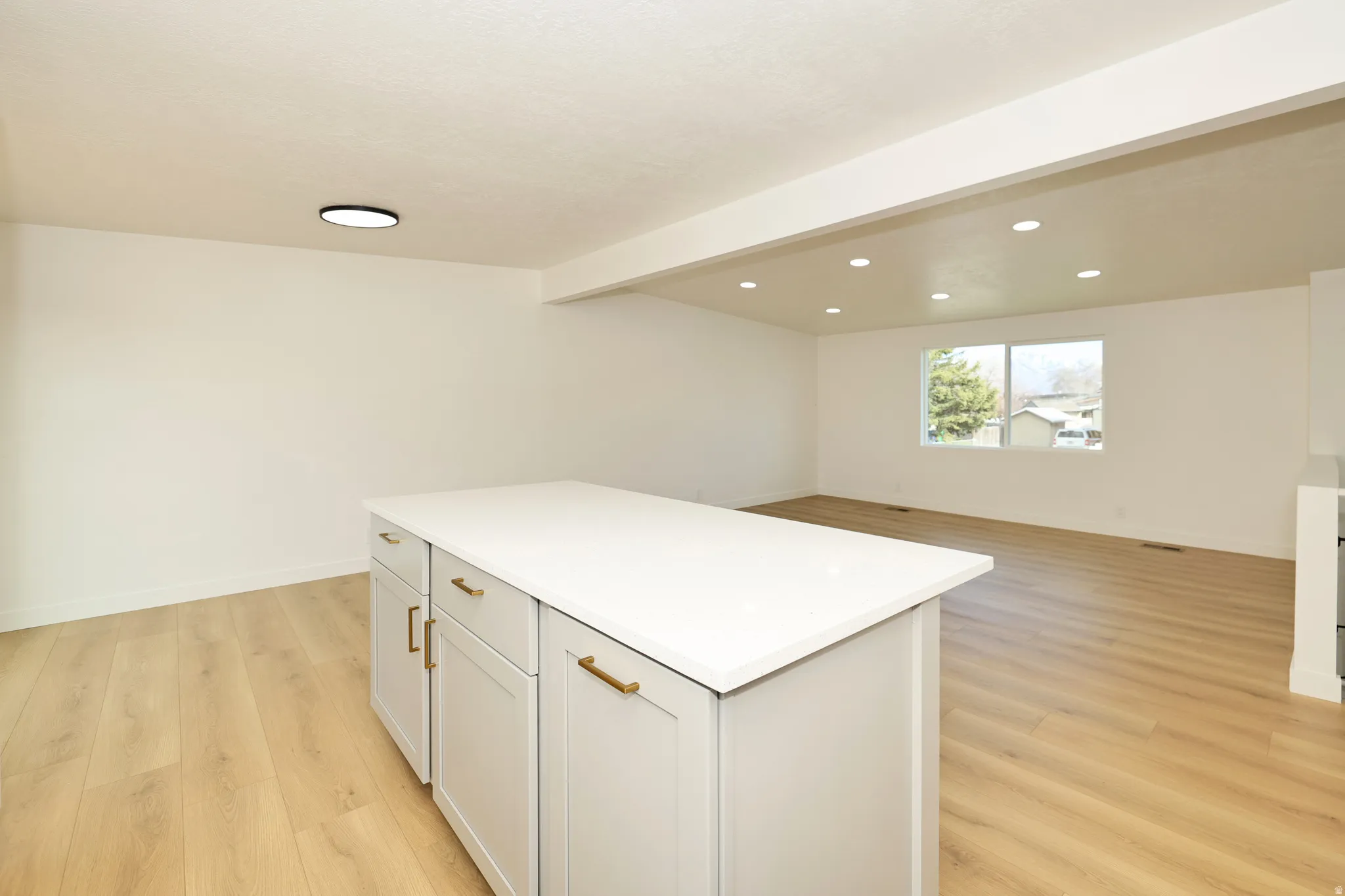 Kitchen with a center island, light wood-style flooring, beam ceiling, open floor plan, and recessed lighting