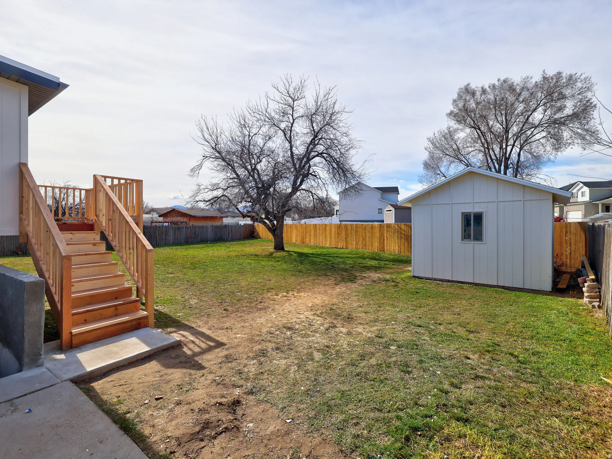 Fenced backyard featuring an outdoor structure and a wooden deck