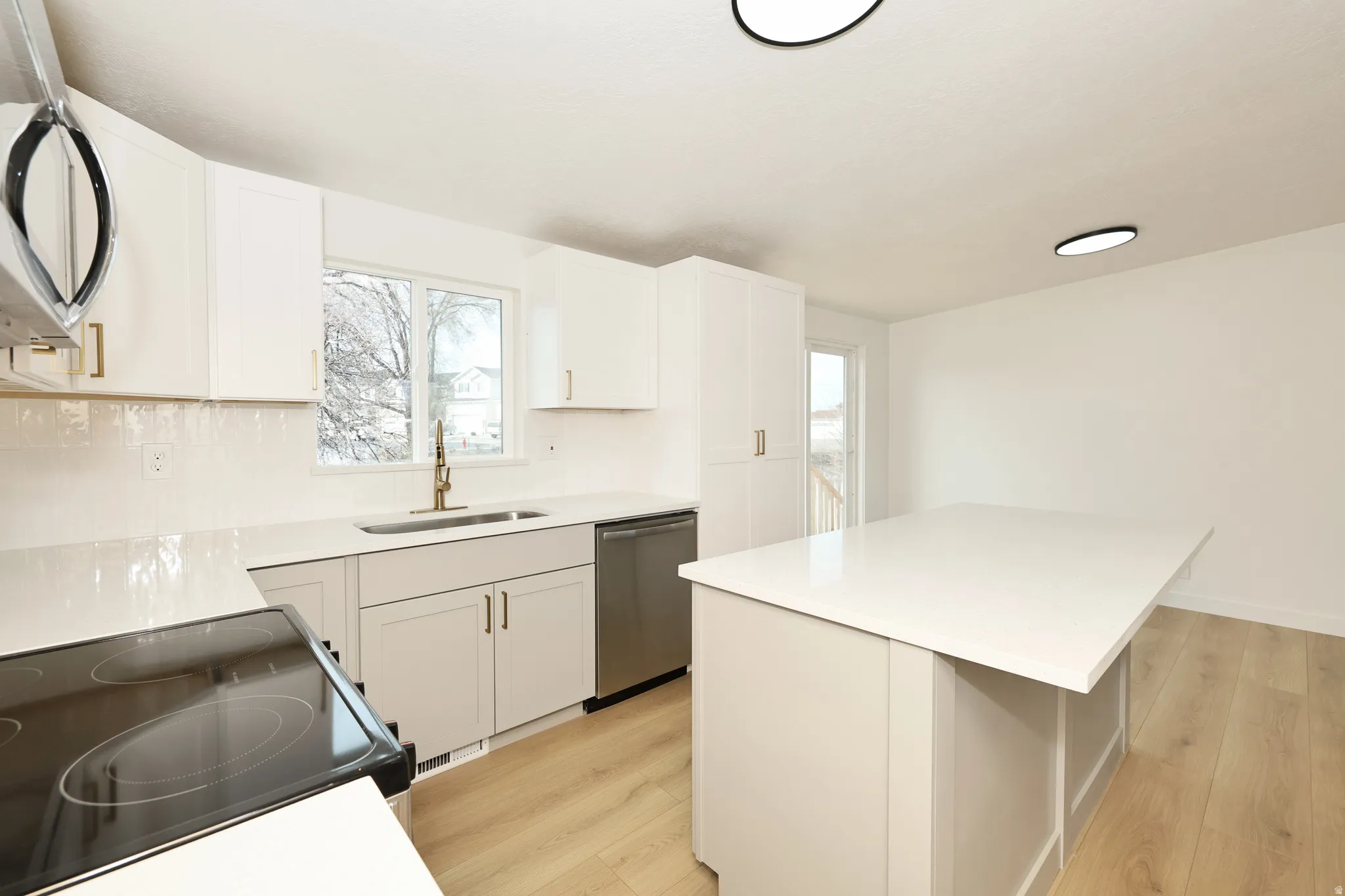 Kitchen with stainless steel appliances, a center island, light wood-style flooring, and white cabinets