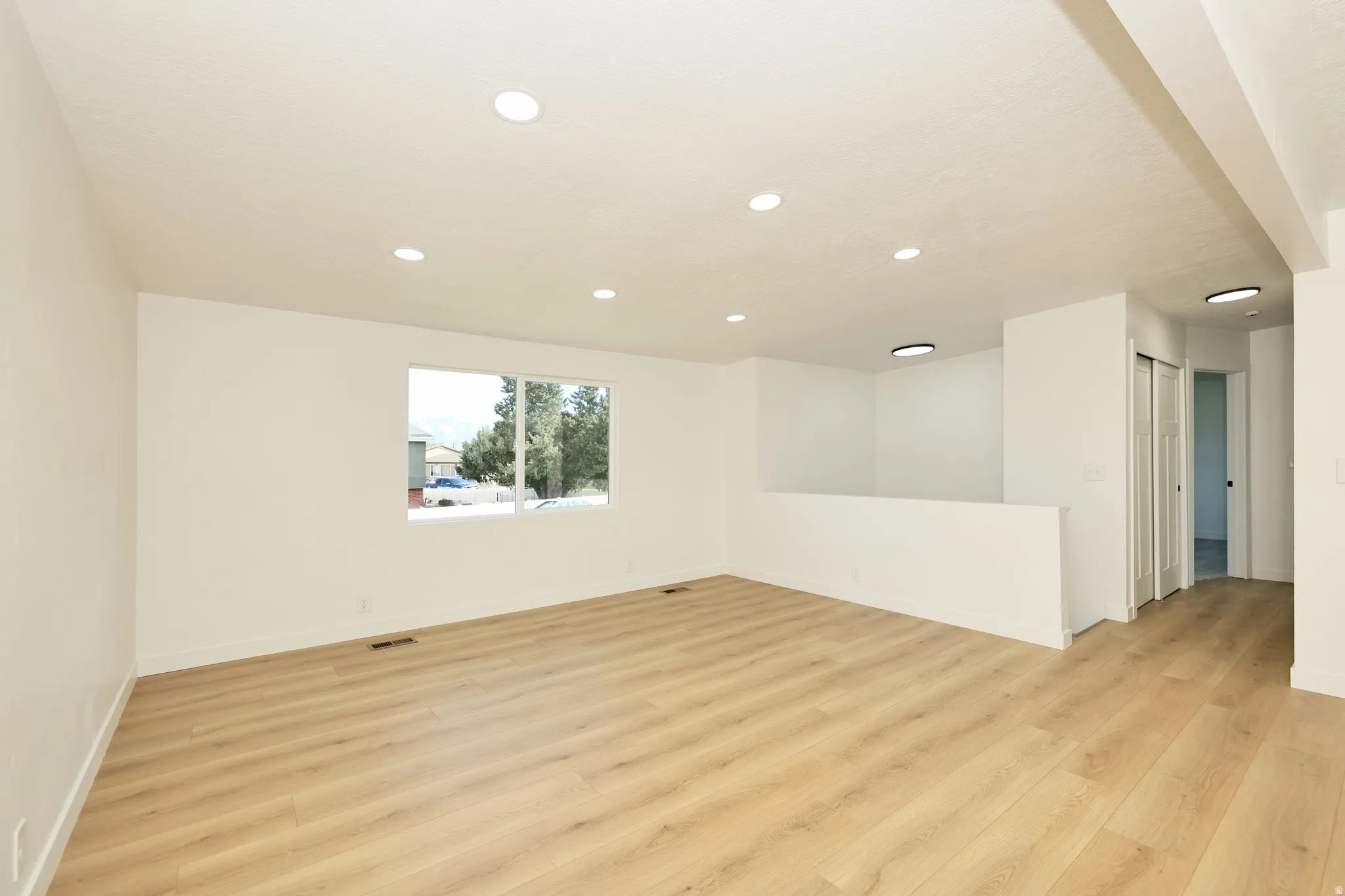 Empty room with light wood-type flooring and recessed lighting