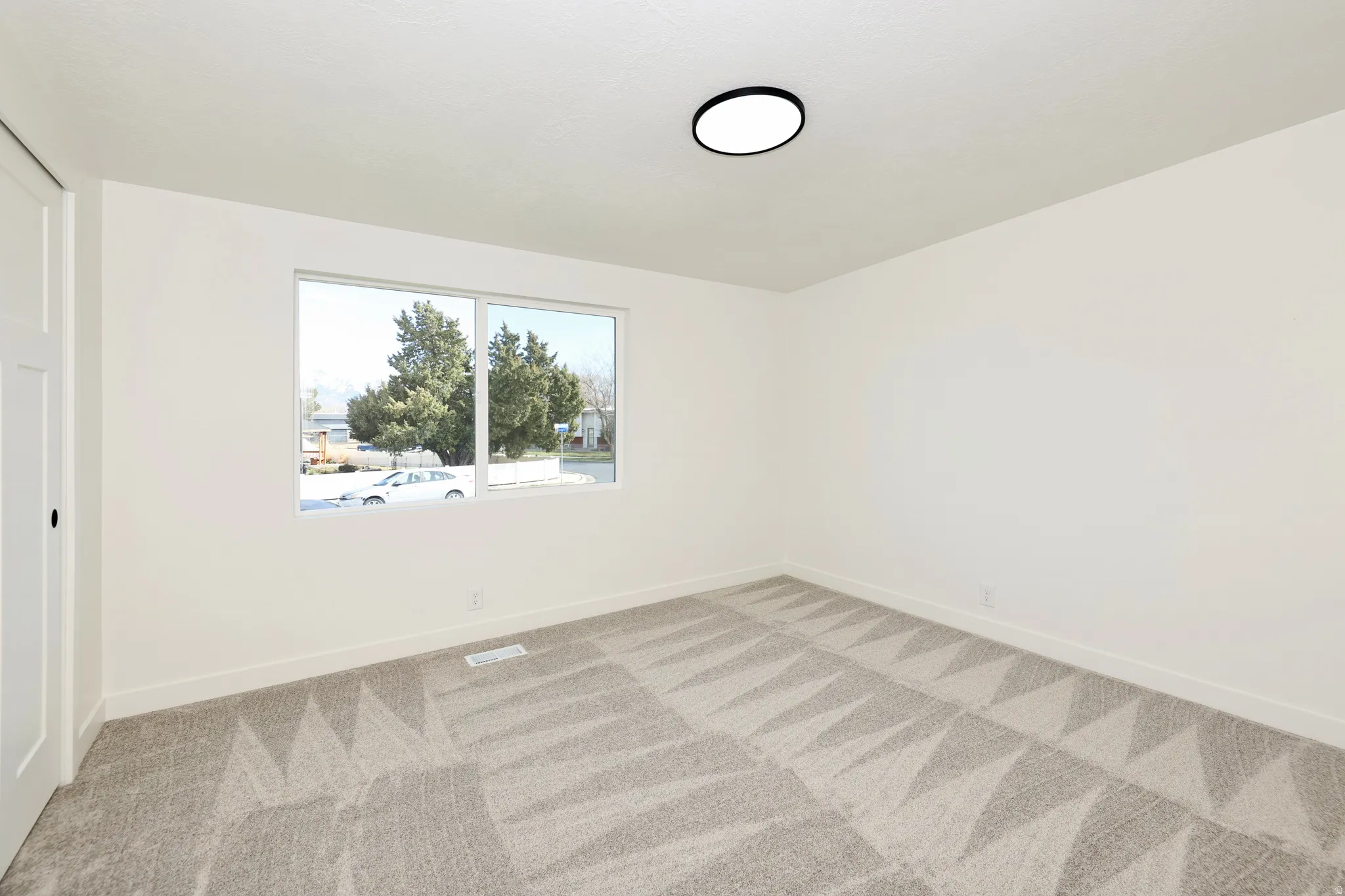 Unfurnished bedroom with light colored carpet and baseboards