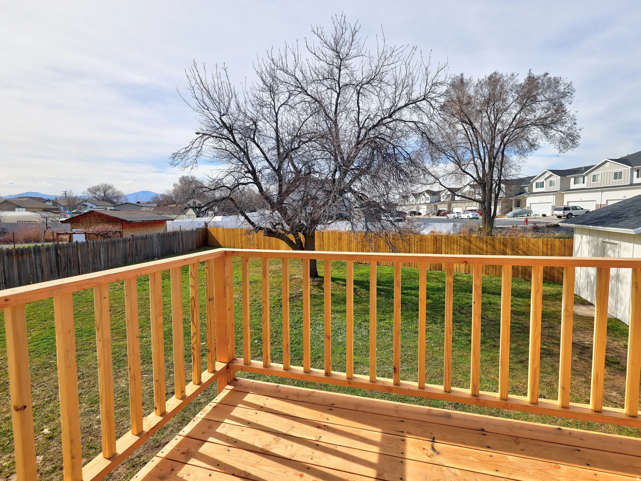 Wooden terrace with a fenced backyard and a residential view