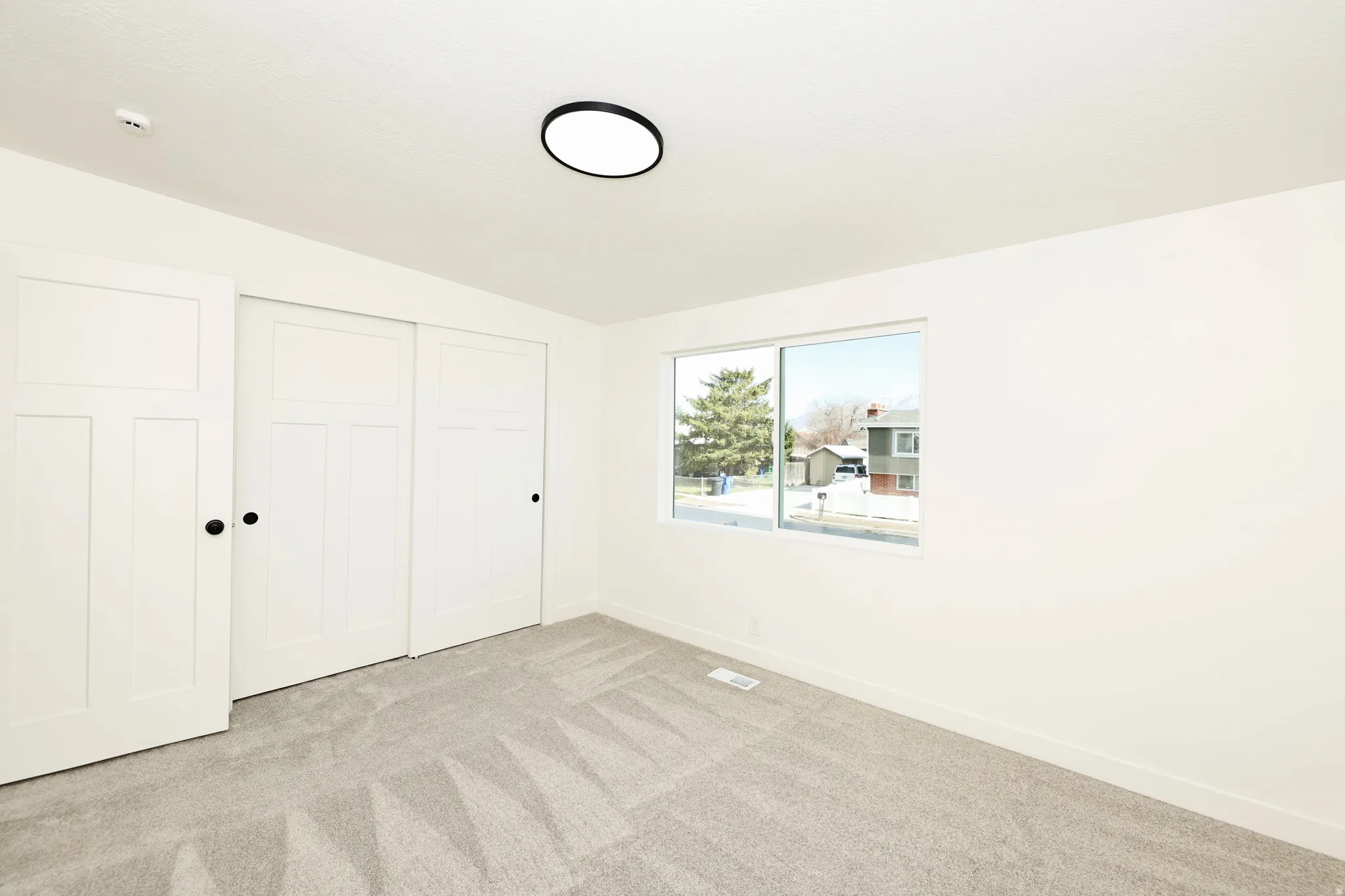 Unfurnished bedroom with lofted ceiling, a closet, and light carpet